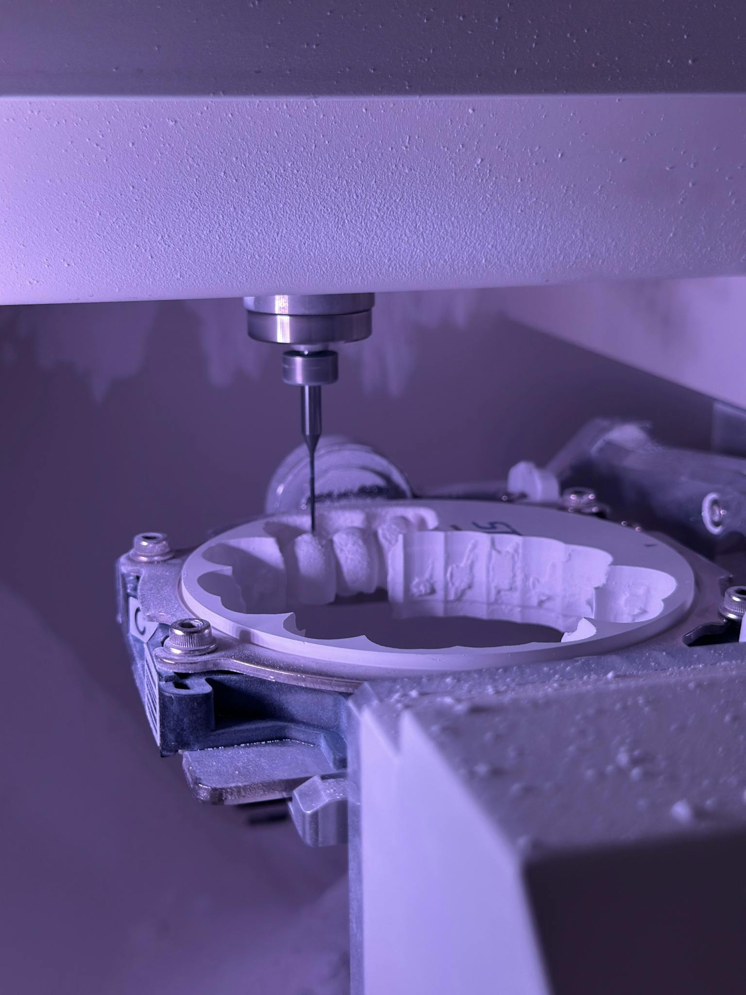 Detailed view of CNC machine milling process with purple lighting, highlighting precision engineering.